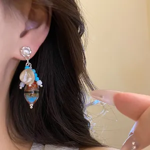 Detailed close-up of vintage-style earrings featuring pearls and shells on an Asian model