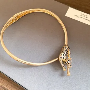 Detailed view of a gold leopard choker necklace with black enamel spots on grey background