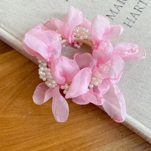 Close-up detail of a pink chiffon flower hair tie accented with decorative white pearls