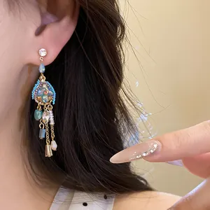 Detail view of elegant vintage drop earrings featuring blue stones and beads worn on ear