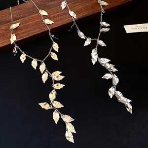 Elegant gold and silver pleated leaf tassel necklaces on a dark textured background.