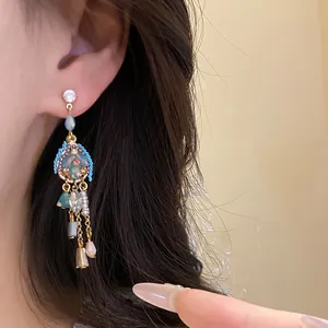 Close-up of vintage dangle earrings with blue stones and pearls on model's ear