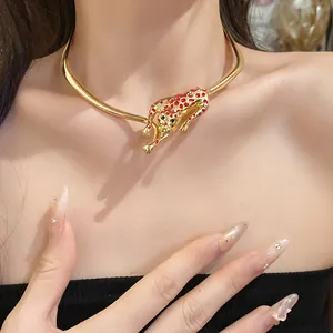 Close-up detail of a gold leopard pendant choker necklace with red enamel accents.