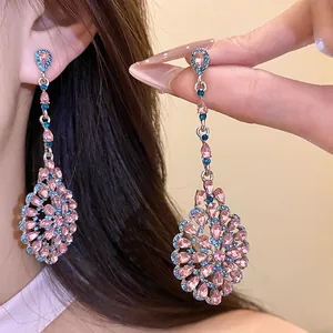 Dettaglio degli orecchini pendenti vintage con strass scintillanti rosa e blu.