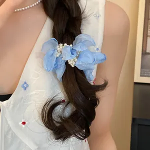 Close-up of blue chiffon flower hair scrunchie with pearl accents in braided hair.