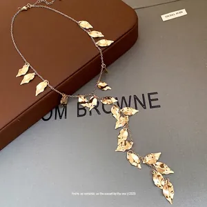Elegant vintage gold-toned wrinkled leaf tassel necklace displayed on a gift box background