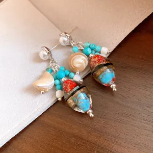 Close-up detail of vintage style earrings with pearls, turquoise, and colorful glass beads.