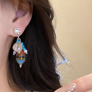Detail shot of vintage pearl and stone drop earrings worn on ear for an elegant look