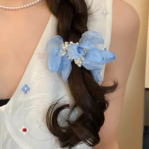 Close-up of blue chiffon flower hair scrunchie with pearls on a braided hairstyle