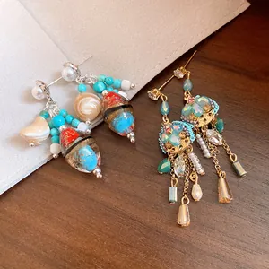Close-up detail of vintage-style earrings featuring colorful beads, shells, and crystals.