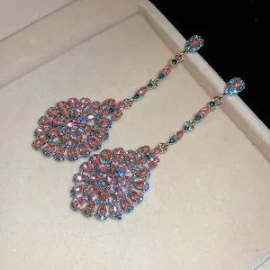 Orecchini pendenti vintage con cristalli rosa e blu in una scatola per gioielli beige