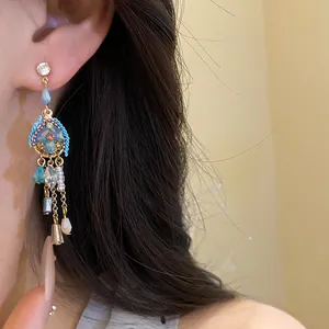 Close-up of vintage style dangling earring with blue crystals and gold-tone chains