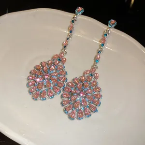 Primo piano di orecchini pendenti vintage con strass rosa e blu scintillanti.