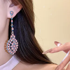 Primo piano di orecchini pendenti vintage con strass rosa e blu scintillanti sull'orecchio