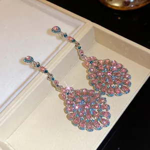 Dettaglio di orecchini pendenti vintage con strass rosa e blu e ago in argento puro.