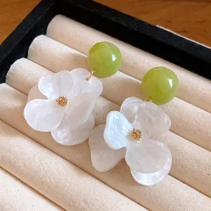 Elegant white flower stud earrings with green beads and a pearlescent marbled finish