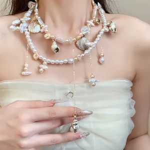 Detailed view of an elegant double-layer necklace with pearls and seashells on a model.
