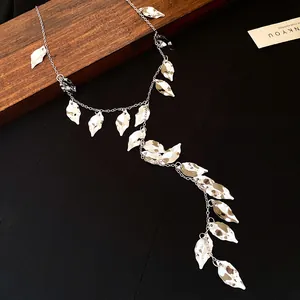 Macro detail of elegant silver pleated leaf charms on a long tassel sweater chain