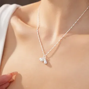 Detailed view of dainty silver peanut and fruit pendants on a fine chain necklace