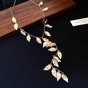 Detailed macro view of a vintage gold-toned leaf tassel necklace on dark fabric