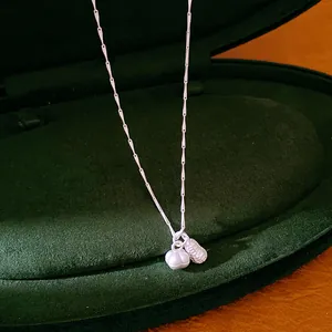 Detailed macro view of silver peanut and spherical charms on a minimalist necklace