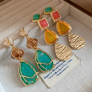 Macro detail of elegant vintage resin water drop earrings with hammered gold finish