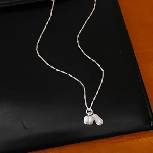 Macro view showing the intricate detail of a silver peanut pendant on a minimalist necklace.