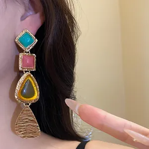 Close-up detail of vintage geometric drop earring with colorful resin and gold finish