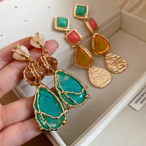 Macro detail of vintage-style gold-tone drop earrings featuring vibrant resin stones