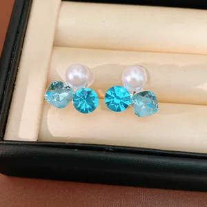 Detailed view of clip-on earrings with white pearl and blue rhinestones in a box