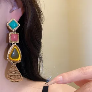 Macro view showing vintage geometric resin drop earrings with gold hammered metal finish