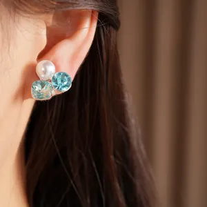 Detailed macro shot of an elegant blue crystal and pearl ear clip worn on a female ear