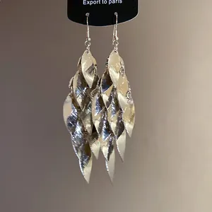 Dettaglio di orecchini a goccia con nappe a foglia in metallo argentato