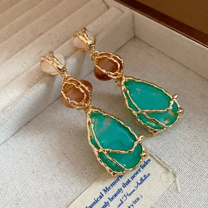 Close-up detail of vintage resin teardrop earrings with elegant gold-tone metal textures