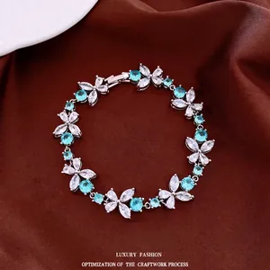 Elegant silver floral bracelet featuring light blue and clear cubic zirconia on brown satin.