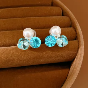 Macro view of elegant clip-on earrings with white pearl and sparkling light blue crystals