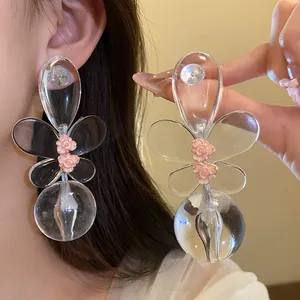 Detailed view of oversized clear butterfly earrings with delicate pink flower accents.