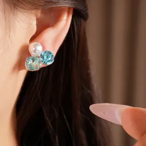 Detailed close-up showing the elegant square and round light blue crystal pearl ear clips