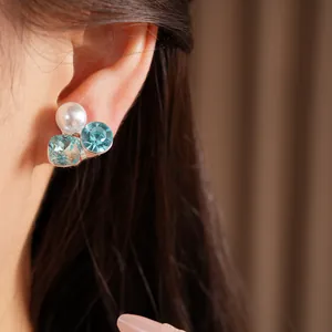 Close-up detail of light luxury elegant pearl and blue crystal clip-on earrings on ear