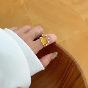 Close-up detail of a minimalist gold-plated ring with yellow resin and small pearls