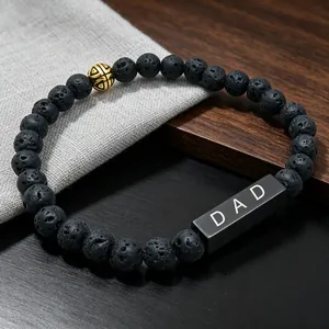 Detailed shot of black lava rock bracelet with engraved DAD block on wooden surface