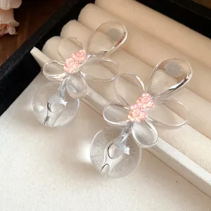 Close-up detail of elegant clear acrylic floral earrings featuring delicate pink rose accents