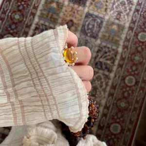 Detailed view of a vintage amber resin open ring with silver bead accents on hand.