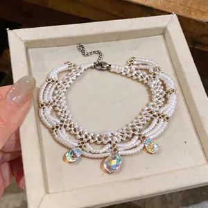 Multi-strand white beaded bracelet with iridescent teardrop glass charms in a gift box
