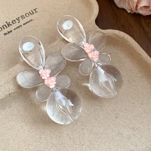 Detailed macro view of clear resin butterfly earrings featuring delicate pink flower accents.