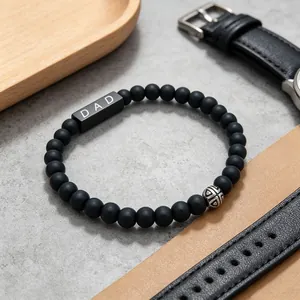Close-up of a Father's Day black agate beaded bracelet with 'DAD' engraving and metal bead.