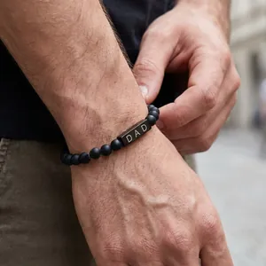 Close-up of matte black onyx bead bracelet with engraved DAD square bead detail