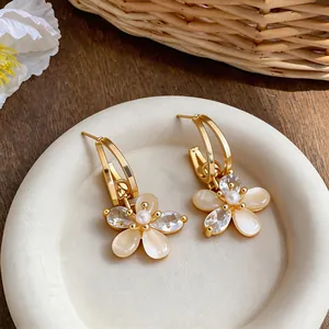 Detail view of 18k gold plated flower stud earrings with zircon and pearl accents
