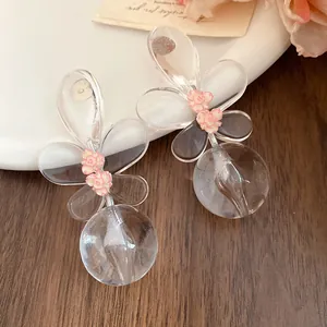 Close-up of elegant clear resin flower drop earrings with small pink floral detail