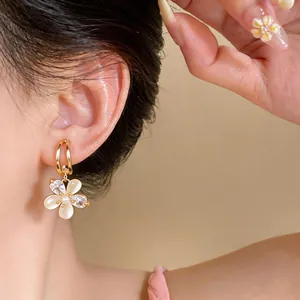 Detail of 18k gold plated zircon flower dangle earring worn on ear